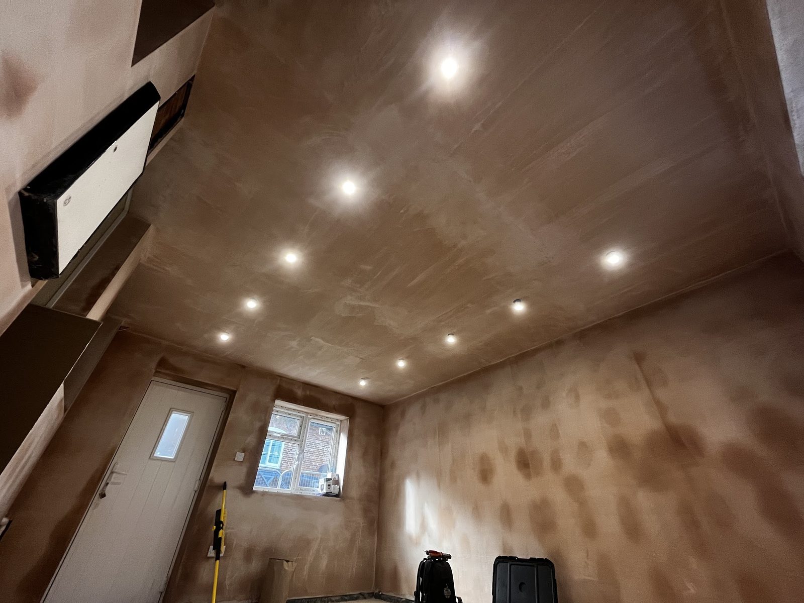 Downlights lit in the ceiling of a freshly plastered room