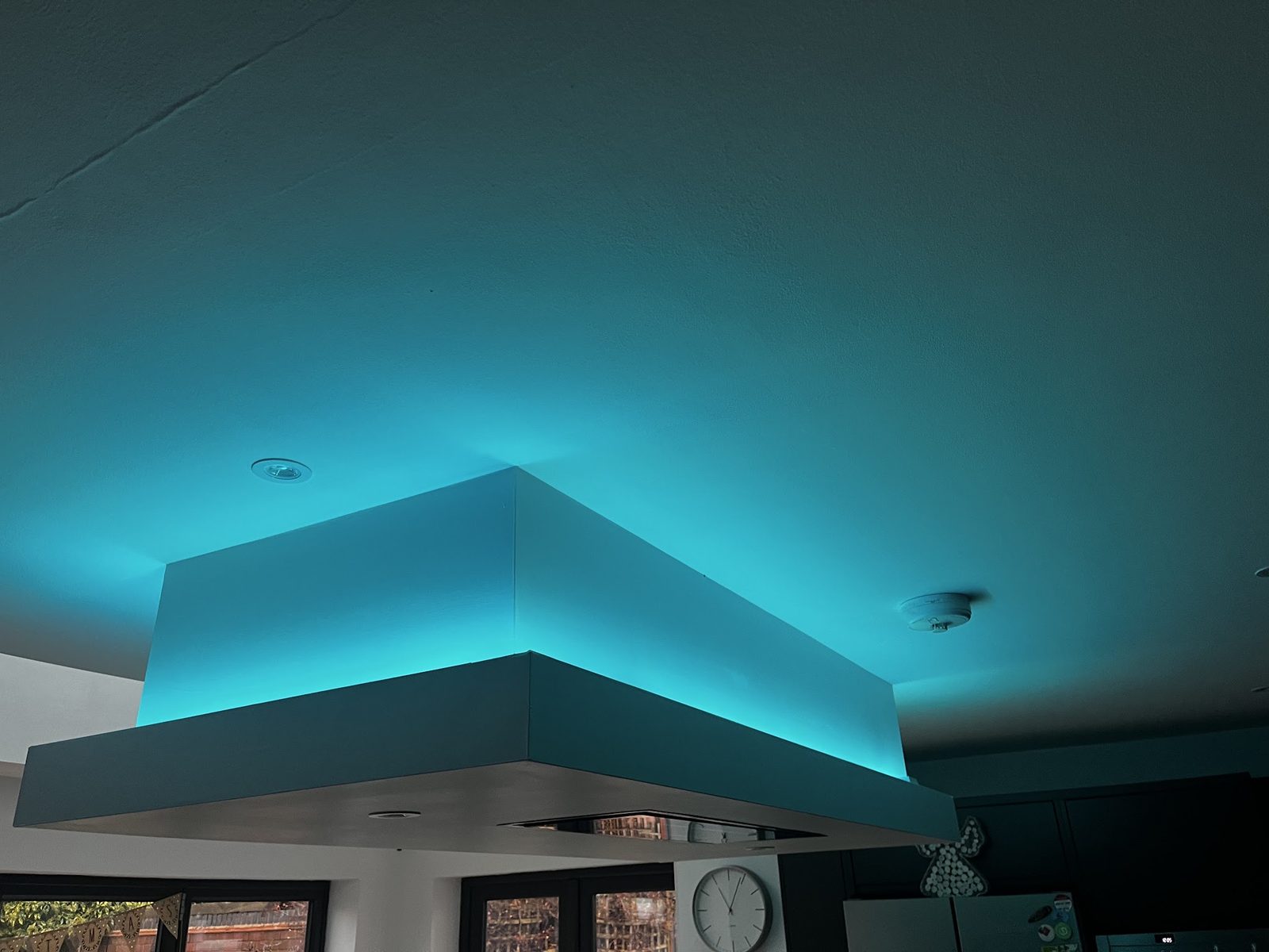 Turquoise LED tape glowing around a kitchen ceiling feature