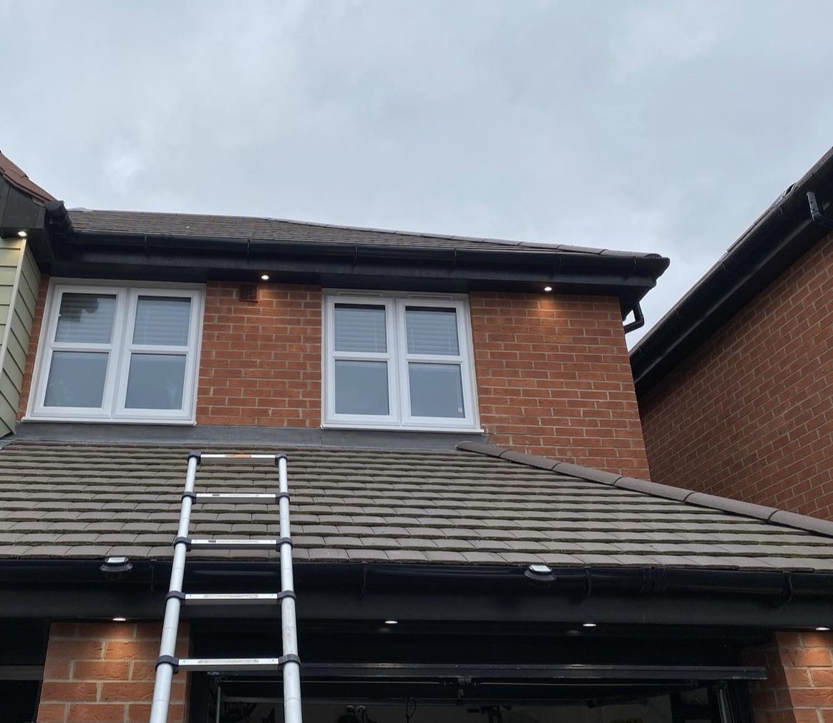 Soffit downlights fitted along the roofline of a brick house
