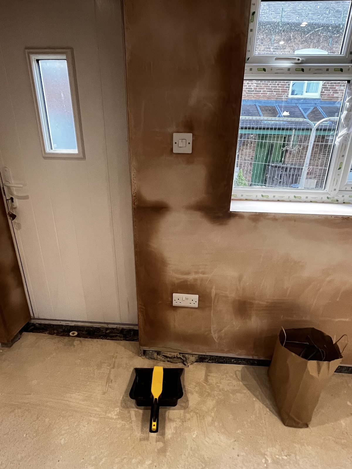 A new double socket and switch fitted beside a back door in a plastered room