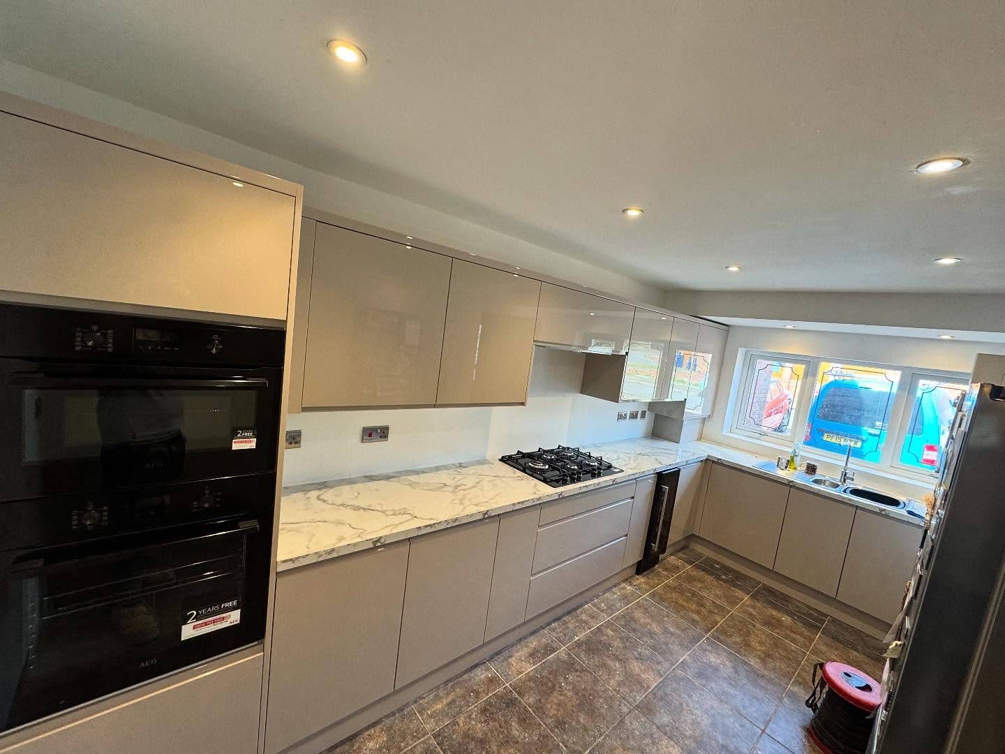 A grey gloss kitchen with downlights, sockets and a double oven