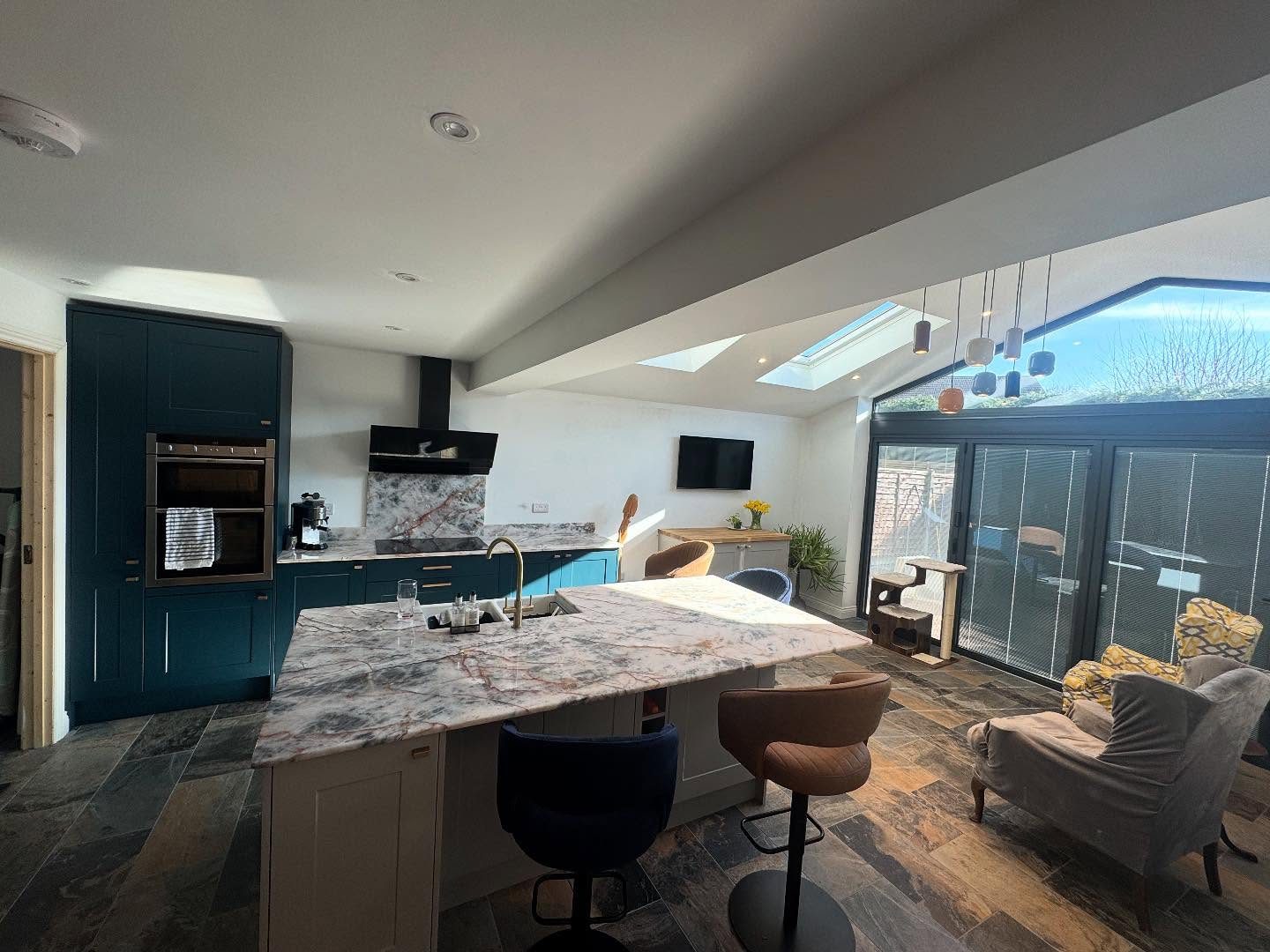 A navy kitchen in a vaulted extension with downlights, pendants over the island and roof windows
